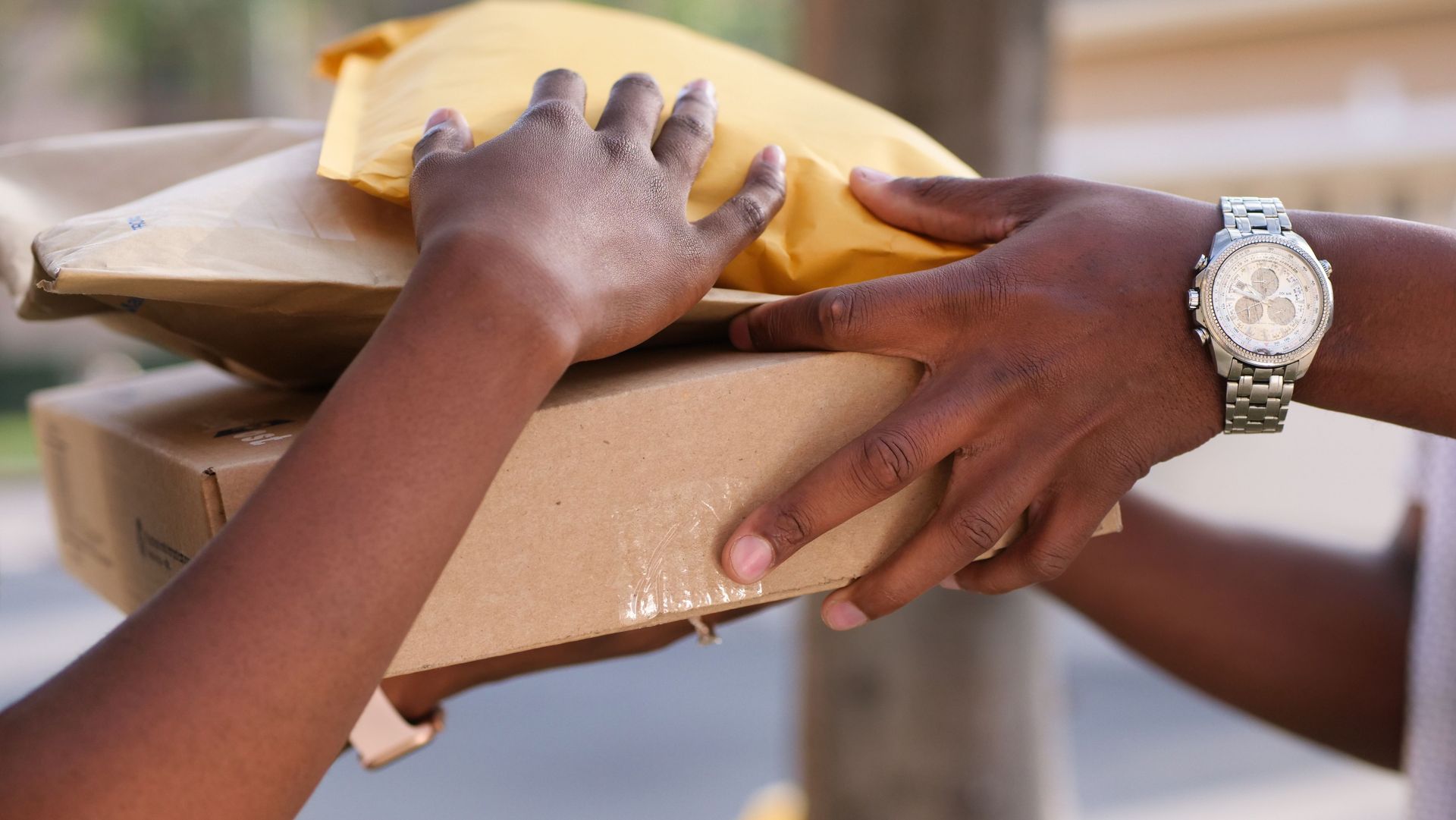 Two individuals exchanging cardboard and padded envelopes, representing delivery services.